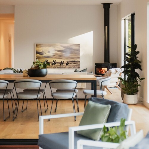 Open-plan living and dining room with wood fire heater in a Greystone custom home, Noosa hinterland